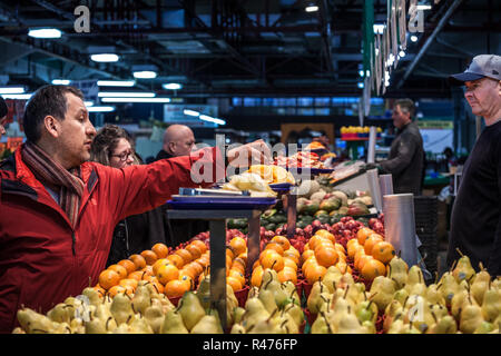 MONTREAL, Canada - 3 Novembre 2018: uomo canadese campioni di degustazione di arance in Jean Talon mercato, a Montreal, in Quebec. È un importante punto di riferimento e un sym Foto Stock