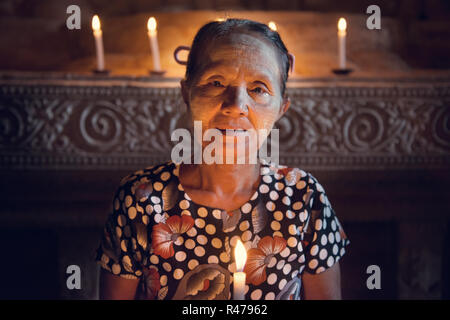 Donna birmano prayingwith lume di candela Foto Stock