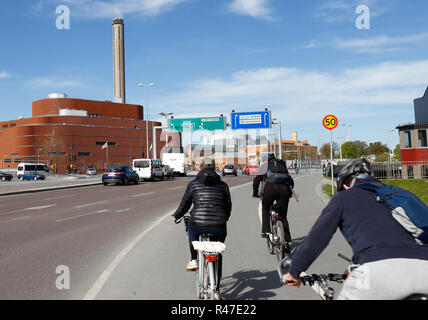 Stoccolma, Svezia - 16 Maggio 2017: I ciclisti ciclo su una pista ciclabile su strada Lidingovagen con Fortum la produzione combinata di calore ed energia elettrica a Hjorthagen distric Foto Stock