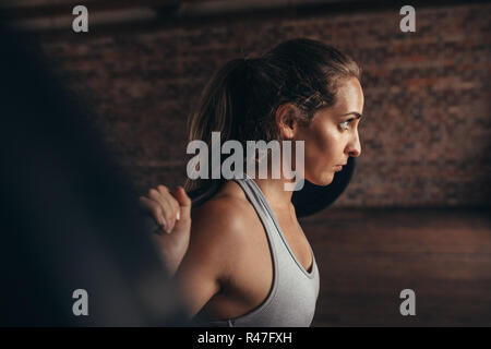 Un sano giovane donna alla palestra esercitando con barbell. Montare la giovane donna che lavora fuori con pesi pesanti a cross training gym. Foto Stock
