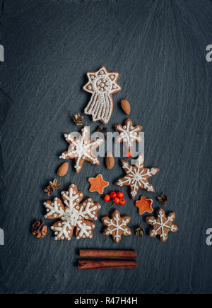 Panpepato, noci, spezie, essiccato a buccia d'arancia crea un albero di Natale al buio su un sfondo di pietra Foto Stock