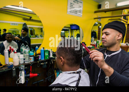 Barbiere dando il suo cliente un taglio di capelli in un barbiere Foto Stock