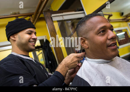 Barbiere dando il suo cliente un taglio di capelli in un barbiere Foto Stock