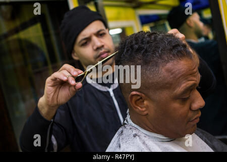 Barbiere dando il suo cliente un taglio di capelli in un barbiere Foto Stock