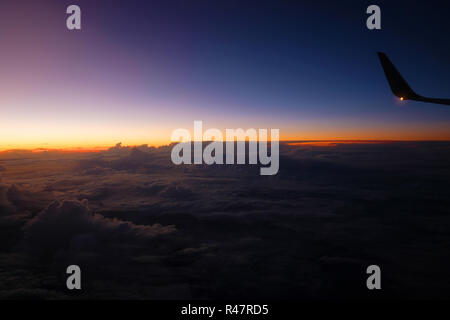 Ala di un piano di fronte a un bel tramonto sopra le nuvole Foto Stock