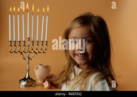 Hanukkah: Bambina sullo sfondo di candele Hanukkah Foto Stock