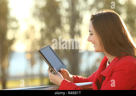 La donna la lettura di ebook al tramonto Foto Stock