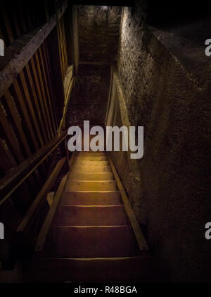 Un vecchio pericolosi scala in legno conduce al buio dungeon Foto Stock