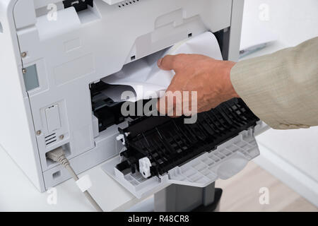 Imprenditore il canto di rimuovere la carta bloccata nella stampante Foto Stock