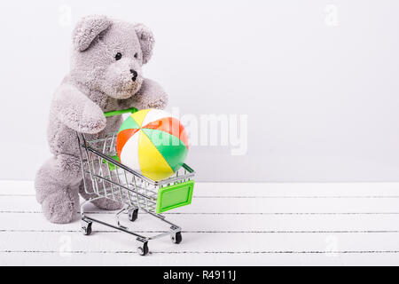 Piccolo carrello e un orso di peluche. Immagine concettuale per la vendita di giocattoli o di bambini&#39 s fantasie Foto Stock