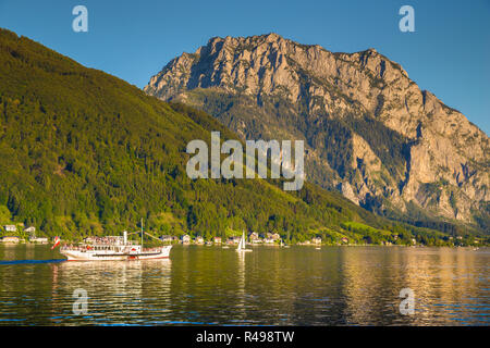 Bellissima vista della tradizionale battello a vapore escursione nave sul Lago Traunsee con il famoso Traunstein mountain in background al tramonto in estate, gm Foto Stock