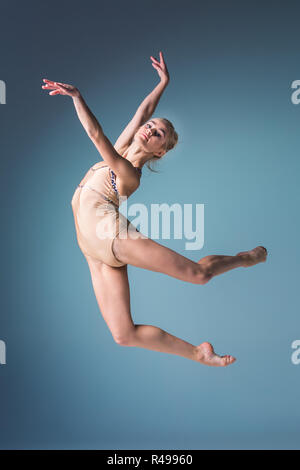 Giovane bella stile moderno ballerina saltando su un sfondo per studio Foto Stock