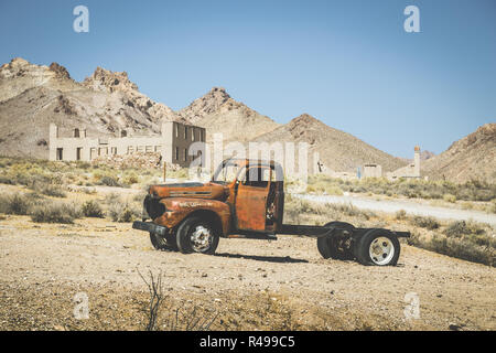 Visualizzazione classica di un vecchio arrugginito pickup truck auto rottamata nel deserto su una bella giornata di sole con cielo blu in estate con retro vintage effetto di filtro Foto Stock