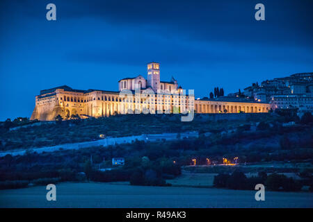 Visualizzazione classica della storica città di Assisi illuminata nella bellissima twilight durante ore Blu al tramonto in estate, Umbria, Italia Foto Stock