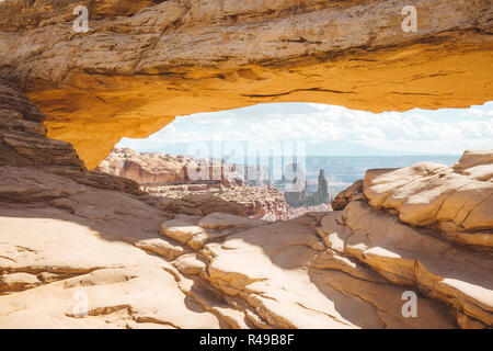 Visualizzazione classica del famoso Mesa Arch, simbolo del sud-ovest americano, illuminata a scenic golden. La luce del mattino al sorgere del sole su una bella giornata in estate Foto Stock