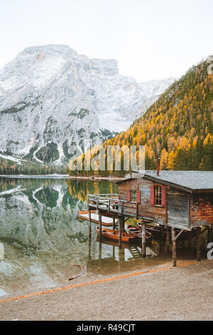 Vista panoramica di legno tradizionali boathouse al famoso Lago di Braies con montagna dolomiti di picchi che si riflettono nel lago, Alto Adige, Italia Foto Stock