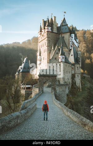 Panorama di young explorer con zaino prendendo in vista sul famoso Castello Eltz a sunrise in caduta, Renania-Palatinato, Germania Foto Stock
