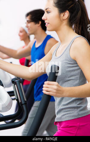 I giovani con macchina ellittica in palestra Foto Stock