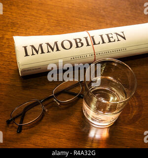 Immobiliare di giornale, bicchiere di acqua, occhiali Foto Stock