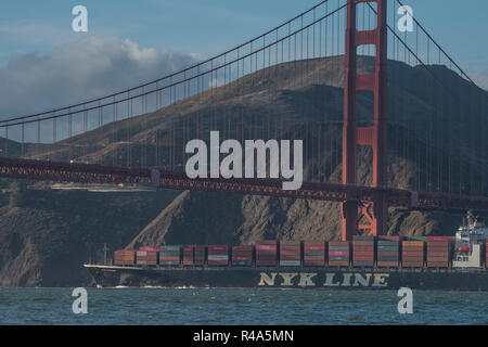 Una nave da carico con carichi di container di spedizione passa sotto il ponte del Golden Gate nel tardo pomeriggio. Foto Stock