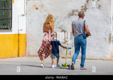 Famiglia giovane a piedi attraverso la città su di una giornata estiva. Foto Stock