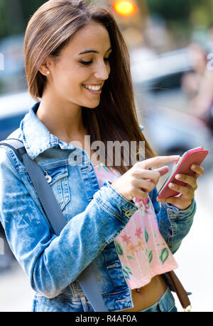 Sorridente bella donna sms con il telefono Foto Stock