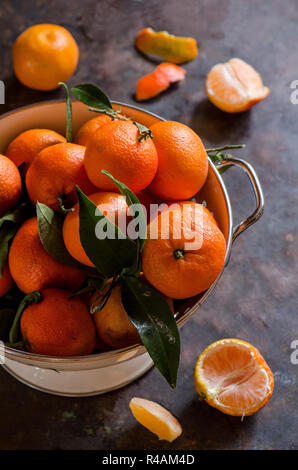 Tangerini in una ciotola su una vecchia scuro dello sfondo in metallo Foto Stock