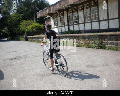 Intorno al Regno Unito - UN ciclista femmina solitaria che passa la stazione ferroviaria in disuso sulla Sustrans Route 69 mantenendo una distanza di sicurezza dagli altri utenti. Foto Stock