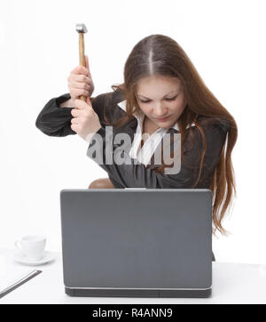 Giovane donna di affari cercando di smash il portatile con un martello Foto Stock