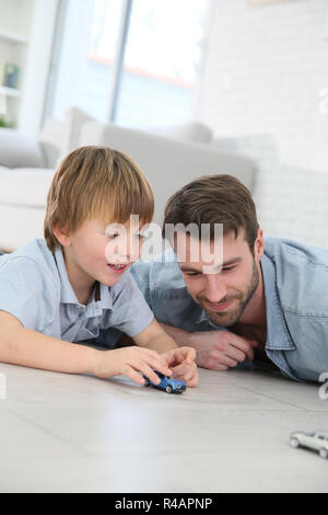 Il papà con piccolo ragazzo giocando con automobili giocattolo Foto Stock