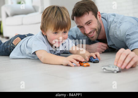 Il papà con piccolo ragazzo giocando con automobili giocattolo Foto Stock