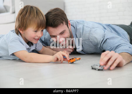 Il papà con piccolo ragazzo giocando con automobili giocattolo Foto Stock