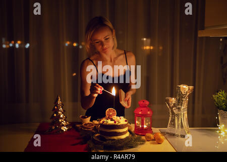 Giovane donna una illuminazione Sparkler nella torta di notte al tempo di Natale Foto Stock