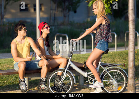 Il gruppo di amici con i pattini a rotelle e in bicicletta nel parco. Foto Stock