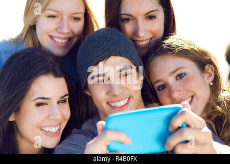 Un gruppo di amici per scattare delle foto con uno smartphone Foto Stock