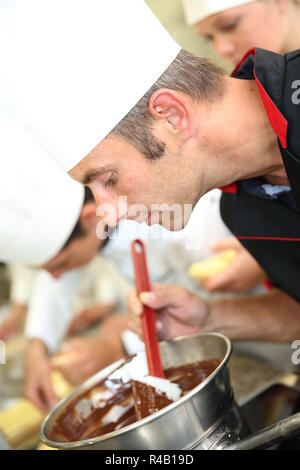 Chef in pasticceria guardando la torta al cioccolato la miscelazione Foto Stock