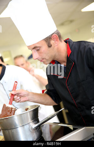 Chef in pasticceria guardando la torta al cioccolato la miscelazione Foto Stock