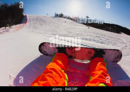 Punto di vista colpo di un maschio di snowboarder seduti sulla neve Foto Stock