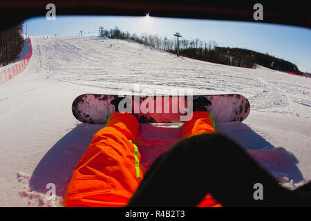 Punto di vista colpo di un maschio di snowboarder seduti sulla neve Foto Stock