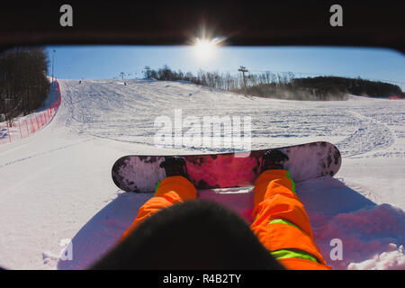 Punto di vista colpo di un maschio di snowboarder seduti sulla neve Foto Stock