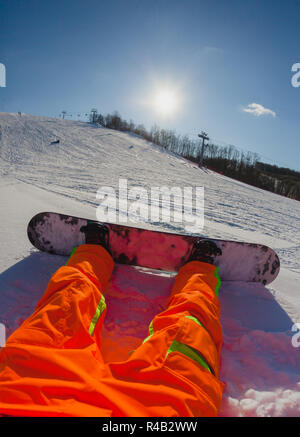 Punto di vista colpo di un maschio di snowboarder seduti sulla neve Foto Stock