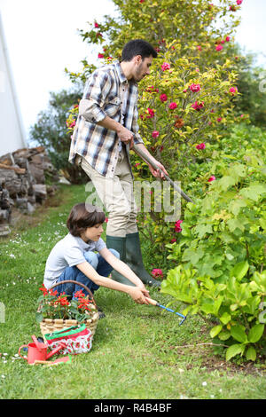Il Daddy insegnamento ragazzino di fare giardinaggio Foto Stock