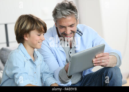 Papà e figlio websurfing sulla tavoletta digitale in casa Foto Stock