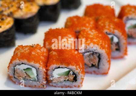 Arancio rotoli di sushi California con caviale in una fila di close-up Foto Stock