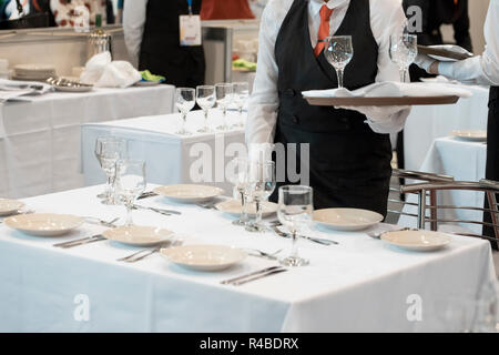 Cameriera vestito in uniforme che serve una serie di bicchieri di vino Foto Stock