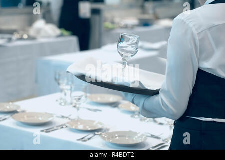 Cameriera vestito in uniforme che serve una serie di bicchieri di vino Foto Stock