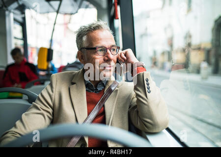 Stanco imprenditore maturo di viaggiare in autobus in città. Foto Stock