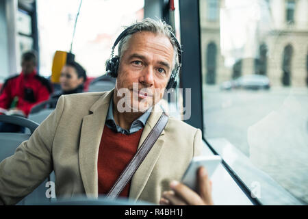 Coppia stanco imprenditore con cuffie e smartpone viaggiare in autobus in città. Foto Stock