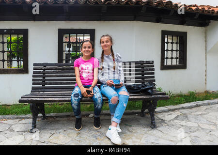 Due ragazze seduti davanti al palazzo della Lega per la difesa dei diritti della nazione albanese o lega di Prizren, Kosovo Foto Stock