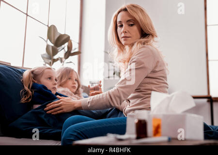 Le responsabilità familiari. Esaurito sconvolto il pensiero di madre mentre è seduto sul letto Foto Stock